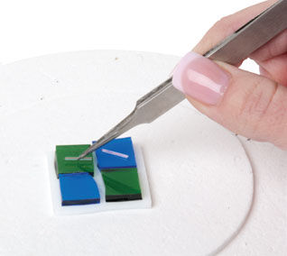 Tweezers placing glass rods onto glass